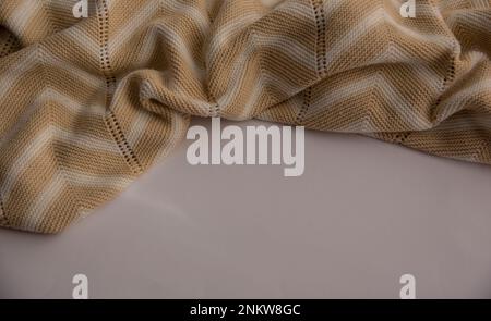 Beige gestrickt mit weißen Streifen auf einer weißen Oberfläche mit Kopierbereich. Herbst, Winter, flach liegend, Draufsicht Stockfoto