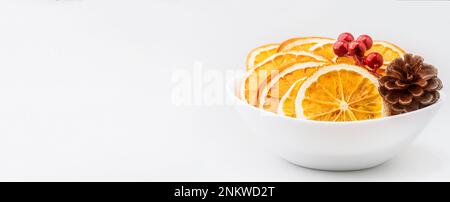 Öko-Bio hausgemachte getrocknete Orangenscheiben, Pommes mit Kiefernzapfen und weihnachtsbeeren. Getrocknete, knusprige Fruchtscheiben. Gesunder Snack. Weihnachten und Ne Stockfoto