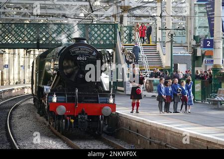 Piper Kevin MacDonald von den Red Hot Chilli Pipers mit Schulkindern von der Royal Scottish Country Dance Society, während einer Veranstaltung am Bahnhof Edinburgh Waverley anlässlich des Tages, als die weltberühmte Lokomotive Flying Scotsman am 24 1923. Februar in Betrieb ging. Foto: Freitag, 24. Februar 2023. Stockfoto