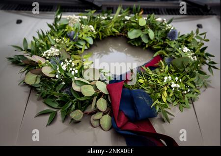 Blumen Bouquets Bouquets und Boutonnieres Blumenkranz mit marineblauen und roten Bändern, die auf der Motorhaube des Autos liegen Stockfoto