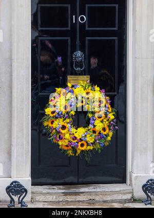 London, Großbritannien. 24. Februar 2023. Ukrainischer Kranz vor der Tür von Nummer 10 der Ministerpräsident Rishi Sunak hält mit minuteÕs seiner Frau Akshata Murty ein Schweigen, um den einjährigen Jahrestag der massiven russischen Invasion in der Ukraine zu feiern. Der ukrainische Botschafter im Vereinigten Königreich, Vadym Prystaiko, wird mit seiner Frau, Mitgliedern der ukrainischen Streitkräfte und Vertretern jeder Interflex-Nation vor der Tür der Downing Street gesessen. Nach der Schweigeminute wurde die ukrainische Nationalhymne gesungen. Kredit: Mark Thomas/Alamy Live News Stockfoto