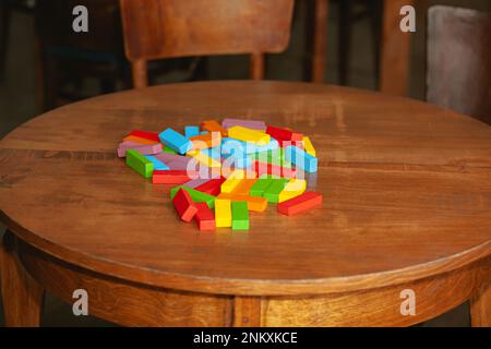 Der zerstörte Turm des Jenga-Spiels. Farbige Blöcke, die auf der Tabelle verstreut sind. Zerstörung, Sturz, Verlust Stockfoto