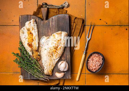 Rotes Meerbarschfilet, Rotbarsch auf Holzbrett. Orangefarbener Hintergrund. Draufsicht Stockfoto