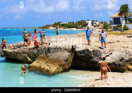 Tres Trapi Beach, Noord, Aruba - 10. März 2022. Menschen am Strand und im Wasser, Strand ist umgeben von einer vulkanischen Felsformation. Stockfoto