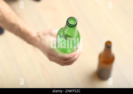 Eine Person hält eine grüne Flasche in der Hand vor dem Hintergrund von Holzbrettern Stockfoto