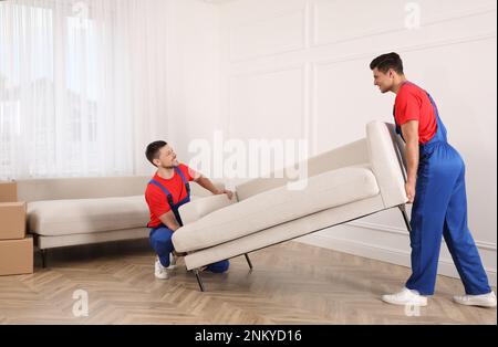 Professionelle Umzugsleute, die ein Sofa im neuen Haus tragen Stockfoto