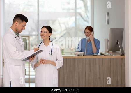 Ärzte, die in der Nähe der Rezeption arbeiten, während sie im Krankenhaus telefoniert Stockfoto