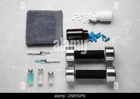Verschiedene Drogen und Sportgeräte auf grauem Hintergrund, flach liegend. Dopingkontrolle Stockfoto