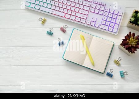 Flache Lagezusammensetzung mit moderner RGB-Tastatur auf weißem Holztisch, Platz für Text Stockfoto