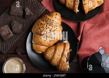 Flache Liegezusammensetzung mit leckeren Croissants, Schokolade und Kaffee auf Holztisch Stockfoto