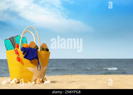 Tasche mit Strandgegenständen auf Sand nahe dem Meer, Platz für Text Stockfoto