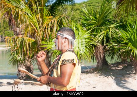 Porträt eines Maya-Musikers, der während einer religiösen Zeremonie in Mexiko am tropischen Strand ein Stammesinstrument spielt Stockfoto