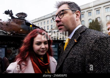 Berlin, Deutschland. 24. Februar 2023. Oleksiy Makeyev (r), Botschafter der Ukraine in Deutschland, und Birdie, ukrainischer Soldat und Sänger aus dem Stahlwerk in Mariupol, stehen vor einem russischen Panzer, der während eines Besuchs in der Ukraine zerstört wurde. Der T-72-Panzer steht auf einem Wohnwagen vor der russischen Botschaft auf der Straße unter den Linden. Diese Aktion soll ein Zeichen des Protests gegen Russlands Krieg sein und Solidarität mit der Ukraine zum Ausdruck bringen. Die russische Armee war am 24. Februar 2022 in die Ukraine eingedrungen. Kredit: Carsten Koall/dpa/Alamy Live News Stockfoto