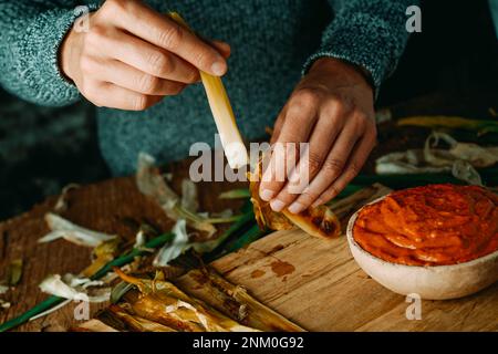 Nahaufnahme eines Mannes, der eine geröstete kalkotte schält, eine süße Zwiebel, die typisch für Katalonien ist, bevor er sie in Romesco-Sauce taucht, wie es üblich ist Stockfoto