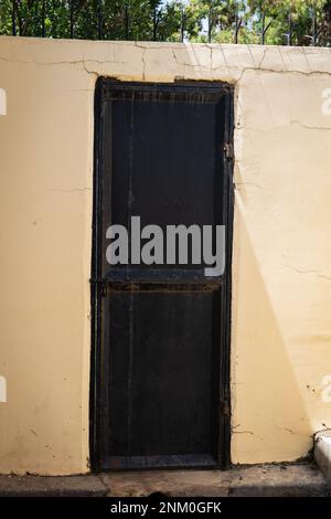 Schwarze Tür, die durch eine gelbe Wand führt Stockfoto