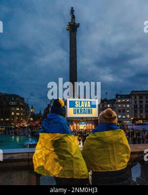 Zwei Demonstranten bei einer Nachtwache am Trafalgar Square anlässlich des ersten Jahrestages der russischen Invasion der Ukraine. Stockfoto