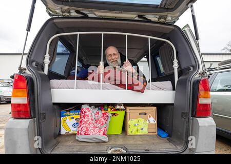 Dresden, Deutschland. 24. Februar 2023. Ein Mann liegt auf einem Bett, das während der Pressekonferenz vor Beginn der 33. stattfindenden Rallye Dresden-Dakar-Banjul in der Werft Laubegast in sein Fahrzeug eingebaut wurde. Die Rallye Dresden-Dakar-Banjul beginnt am 25. Februar 2023 in Hohnstein (Sachsen) mit dem Ziel Gambia, wo die Fahrzeuge versteigert und die Erlöse an die NRO „Dresden-Banjul Organization“ gespendet werden. Kredit: Daniel Schäfer/dpa/Alamy Live News Stockfoto