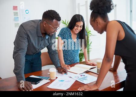 Drei Kollegen stehen an einem Konferenztisch über Finanzberichte Stockfoto