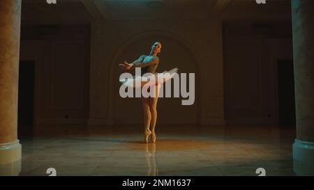 Filmaufnahme einer wunderschönen klassischen Balletttänzerin im weißen Tutu-Kleid, die im Theatersaal tanzt und sich auf den Beginn der Vorstellung vorbereitet. Choreographie vor Beginn der Show. Klassische Ballettkunst Stockfoto