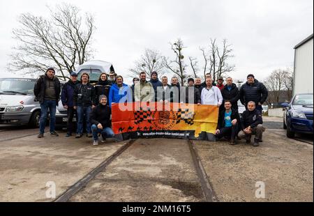 Dresden, Deutschland. 24. Februar 2023. Vor Beginn der 33. stattfindenden Rallye Dresden-Dakar-Banjul in der Werft Laubegast stehen die Teilnehmer für ein Gruppenfoto während der Presseveranstaltung zusammen. Die Rallye Dresden-Dakar-Banjul beginnt am 25. Februar 2023 in Hohnstein (Sachsen) mit dem Ziel Gambia, wo die Fahrzeuge versteigert und die Erlöse an die NRO „Dresden-Banjul Organization“ gespendet werden. Kredit: Daniel Schäfer/dpa/Alamy Live News Stockfoto