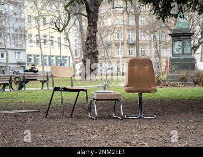 24. Februar 2023, Hessen, Frankfurt/Main: Einladend mit Blumen, zwei Stühlen und einem Stuhlstand am Rande einer Grünfläche neben einem Café im Freien, obwohl die möglichen Gäste sich nicht an die vorherrschende Kälte gewöhnen wollen. Foto: Frank Rumpenhorst/dpa Stockfoto