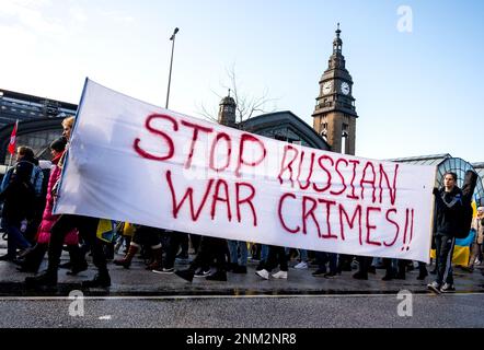 Hamburg, Deutschland. 24. Februar 2023. Teilnehmer einer Demonstration gegen den Krieg in der Ukraine halten ein Banner mit der Inschrift "Stopp russische Kriegsverbrechen". Die russische Armee war am 24.02.2022 in die Ukraine eingedrungen. Kredit: Daniel Bockwoldt/dpa/Alamy Live News Stockfoto