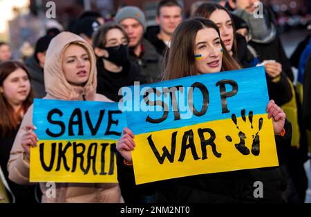 Hamburg, Deutschland. 24. Februar 2023. Teilnehmer einer Demonstration gegen den Krieg in der Ukraine halten Schilder mit der Aufschrift "Save Ukraine" und "Stop war". Die russische Armee war am 24.02.2022 in die Ukraine eingedrungen. Kredit: Daniel Bockwoldt/dpa/Alamy Live News Stockfoto