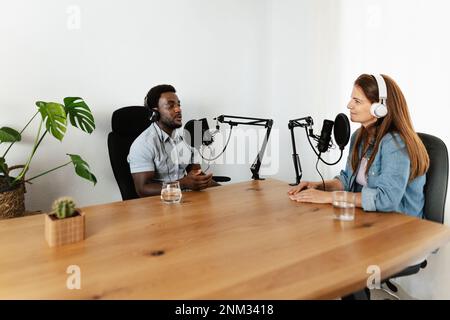 Menschen mit mehreren Rassen, die einen Podcast mit Mikrofon und Kopfhörern aus dem Heimstudio aufnehmen Stockfoto