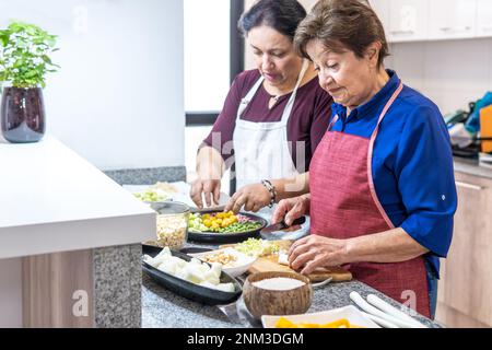 Eine ältere Frau und eine in ihren 40s, die die Fanesca zubereitet Stockfoto