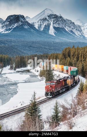 Aussichtspunkt der Morants Curve im Banff National Park, Alberta, Canad, mit dem berühmten roten Frachtzug, der im Winter durch das Bugtal und die felsigen Berge fährt Stockfoto