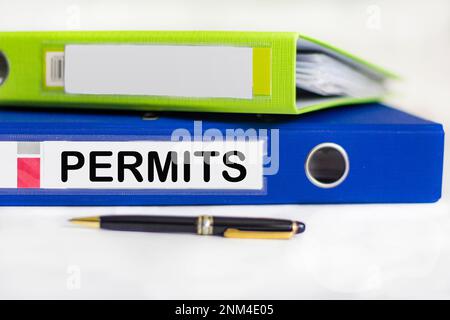 Auf dem Desktop befinden sich Notizbücher, ein Stift und ein blauer Ordner für Papiere mit SCHREIBBERECHTIGUNGEN. Geschäftskonzept Stockfoto