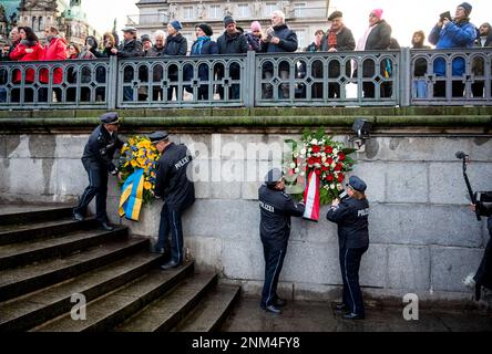 Hamburg, Deutschland. 24. Februar 2023. Polizeibeamte hängen Kränze an einem Gedenken an den Krieg in der Ukraine am Rathausmarkt. Die russische Armee war am 24.02.2022 in die Ukraine eingedrungen. Kredit: Daniel Bockwoldt/dpa/Alamy Live News Stockfoto