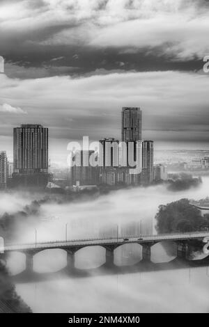 Nebliger B&W-Blick auf die Congress Bridge über den Ladybird Lake in Austin, Texas. Stockfoto