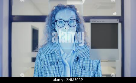 Frau scannt Gesicht im Büro. Sie berührt Sensoren und Sicherheitssysteme. 3D-Hologramm der menschlichen biometrischen Gesichtserkennung und persönliches virtuelles Profil. Datenschutz, Identifikation und KI-Technologie Stockfoto