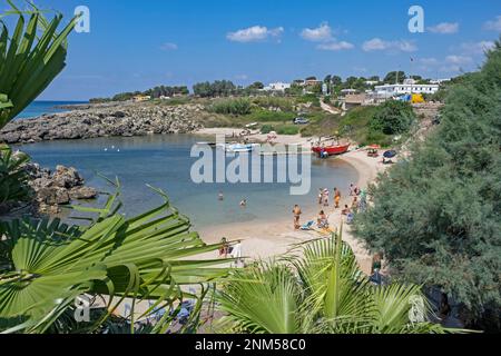 Italienische Touristen schwimmen und sonnen sich im Sommer am Sandstrand entlang des Ionischen Meeres in der Provinz Lecce, Apulien in Süditalien Stockfoto