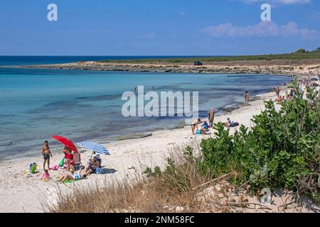 Italienische Touristen schwimmen und sonnen sich im Sommer am Sandstrand entlang des Ionischen Meeres in der Provinz Lecce, Apulien in Süditalien Stockfoto