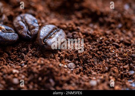 Nahaufnahme von frisch gemahlenem Kaffeepulver und drei Kaffeebohnen Stockfoto