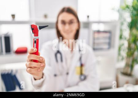 Junge Kaukasierin, die Otoskop in der Klinik hält Stockfoto