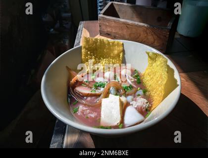 Yentafo Eiernudeln Suppe mit rosa Sauce und Fischbällchen, Garnelen, frischer Tintenfisch, frischer Tintenfisch, eingelegter Tintenfisch, Quallen, Tofu und gebratene Wontons mit Witz Stockfoto