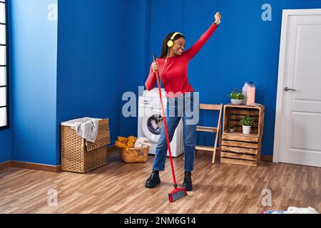 Eine afroamerikanische Frau putzt den Boden und tanzt in der Wäscherei Stockfoto