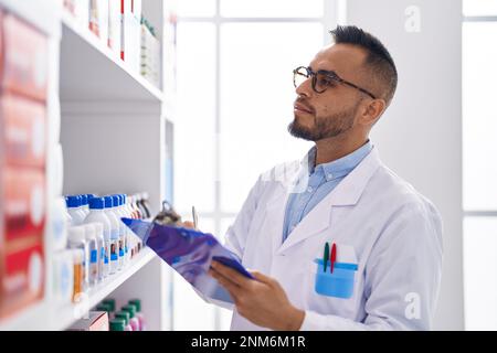 Junger hispanischer Apotheker, der auf einem Dokument in der Apotheke schreibt Stockfoto