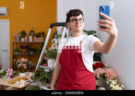 Nicht binärer männlicher Florist macht Selfie per Smartphone im Blumenladen Stockfoto