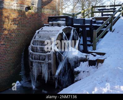 Alte restaurierte Wassermühle in Wilsum, Deutschland nach einer extrem kalten Nacht im Winter. Es ist Schnee. Das fließende Wasser hat sich in Eiszapfen verwandelt Stockfoto