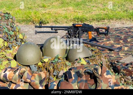 Ein sowjetisches PK-Maschinengewehr mit drei Militärhelmen und Tarnnnetzen. Kalaschnikows Maschinengewehr Stockfoto