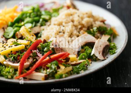 Hausgemachter asiatischer Grünkohl-Salat mit Quinoa, Karotten, Fava-Bohnen, Paprika, Babykorn, Pilze und geräucherter Tofu Stockfoto