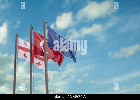 Georgische, türkische und Unionsflaggen vor blauem wolkigen Himmel Stockfoto