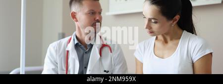Der männliche Arzt kommuniziert mit der weiblichen Patientin in der Klinik Stockfoto