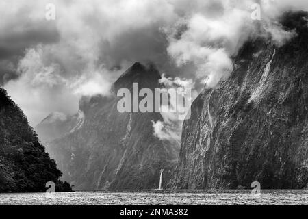 Dramatische stürmische Wolken über dem Mitre Peak und Felsenberge rund um den Milford Sound Fjord in Neuseeland. Stockfoto