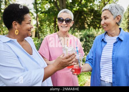 Eine vielfältige Gruppe von Seniorinnen, die im Park Drinks im Freien genießen Stockfoto