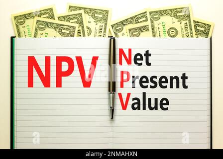 NPV net present value symbol. Concept words NPV net present value on white note on a beautiful background from dollar bills. Pen. Business and NPV net Stockfoto